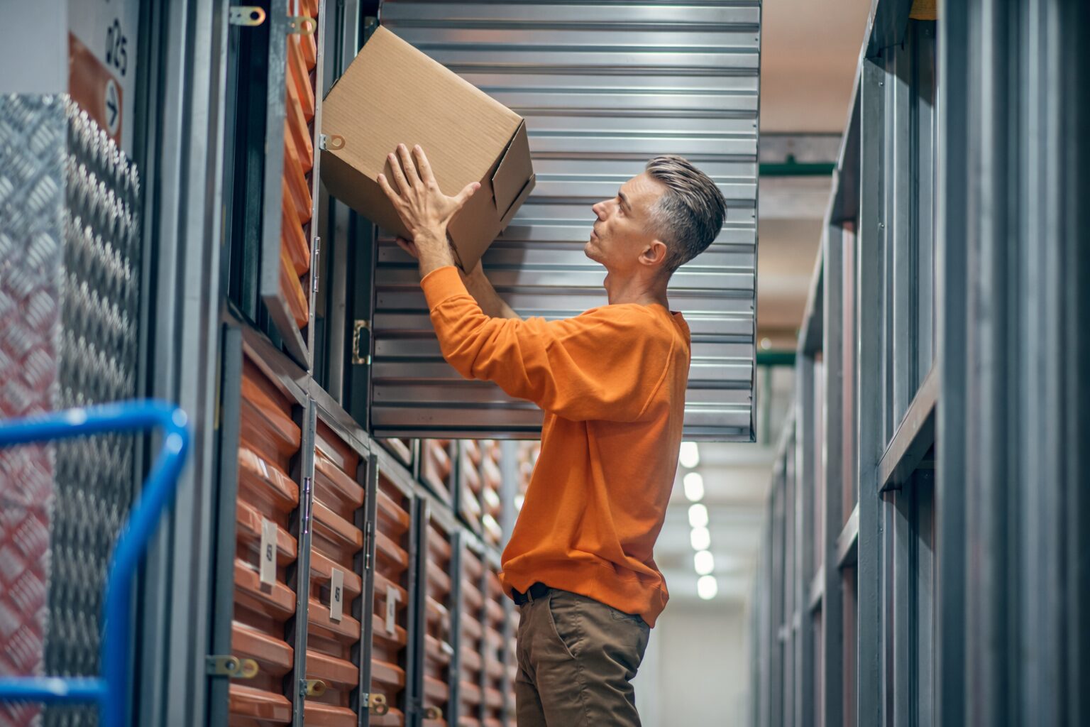 person puttin a cardboard box on a metal shelf