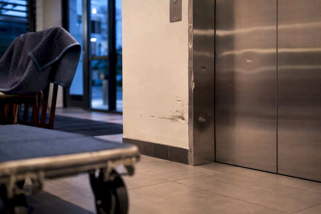 Elevator door dent and hallway paint scrapes