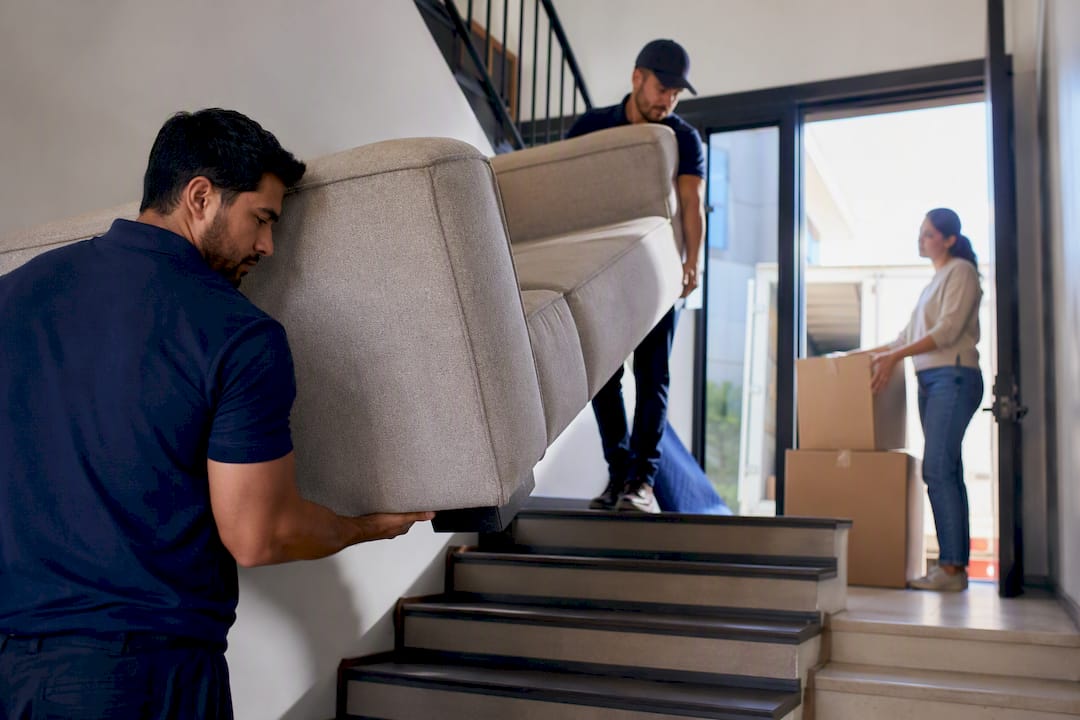 Movers navigating sectional sofa on stairs